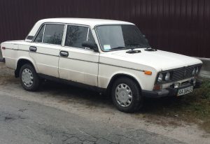 A picture of an old white lada on the side of the road in Kiev, Ukraine
